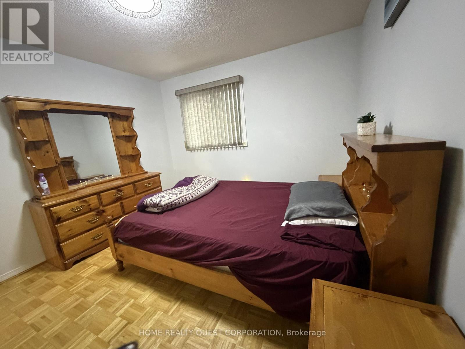 A bedroom with a bed, dresser, and mirror.