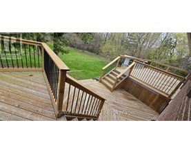 A deck with a railing and stairs leading to a grassy area.