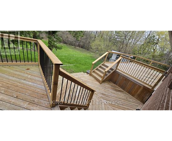 A deck with a railing and stairs leading to a grassy area.