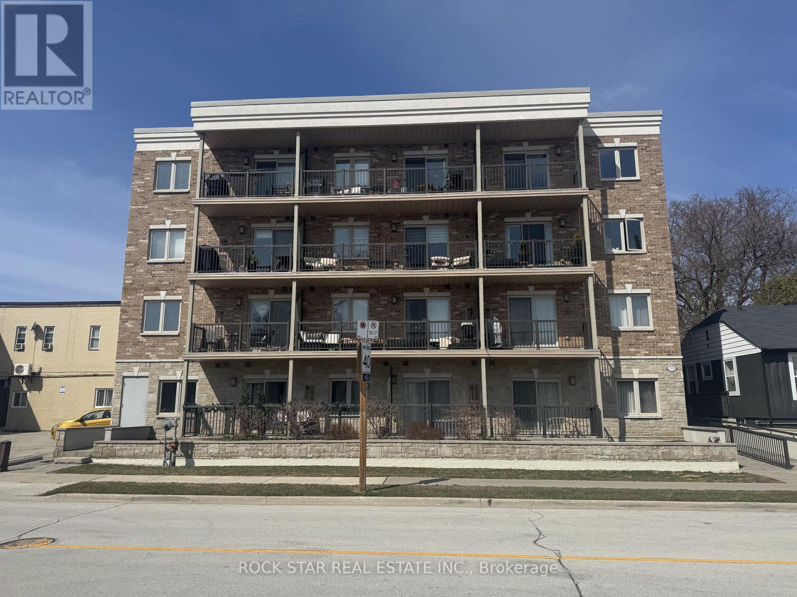 A multi-story apartment building with balconies and a sign for Rock Star Real Estate Inc. in the foreground.