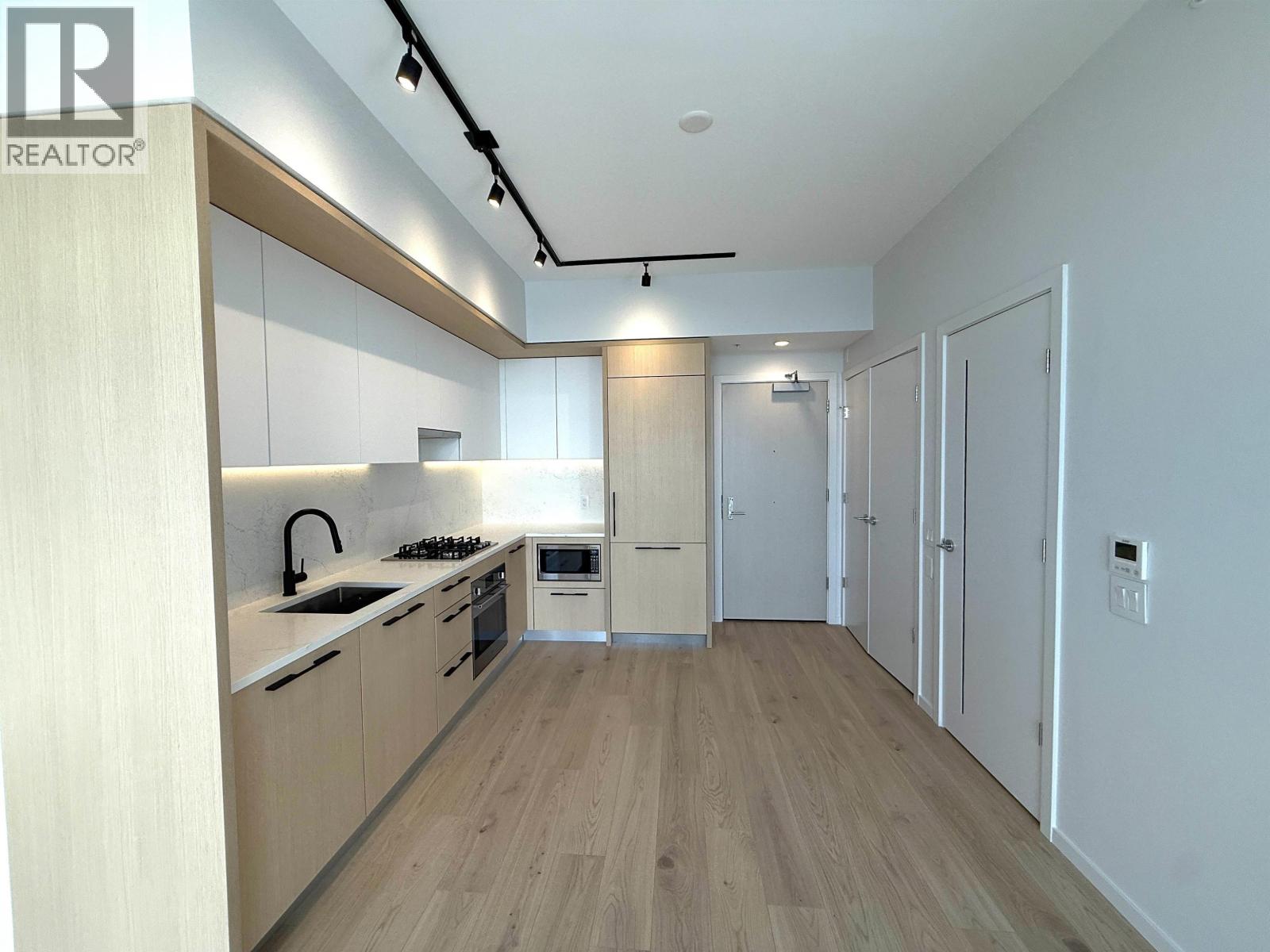 A modern kitchen with wooden cabinets and a white backsplash.