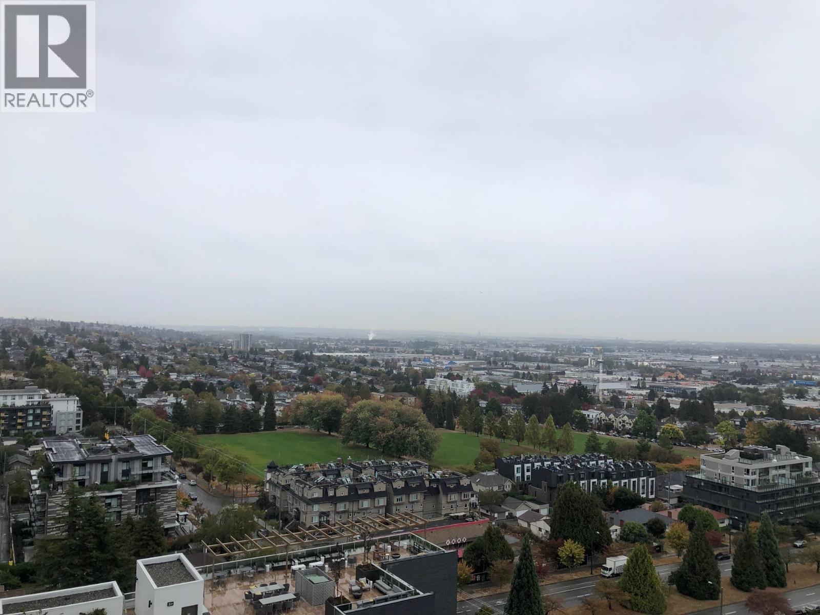 A cityscape with buildings and trees under a cloudy sky.