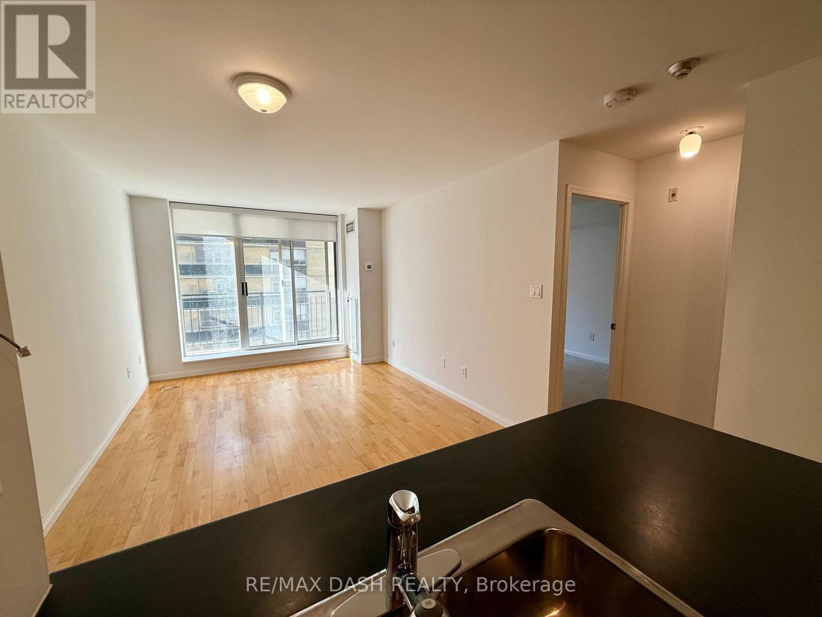 A spacious room with a large window and wooden flooring.