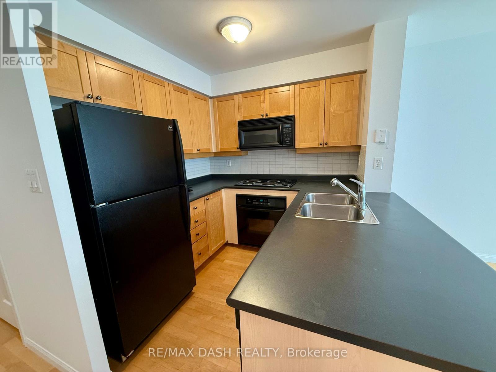 A kitchen with a black fridge and wooden cabinets.