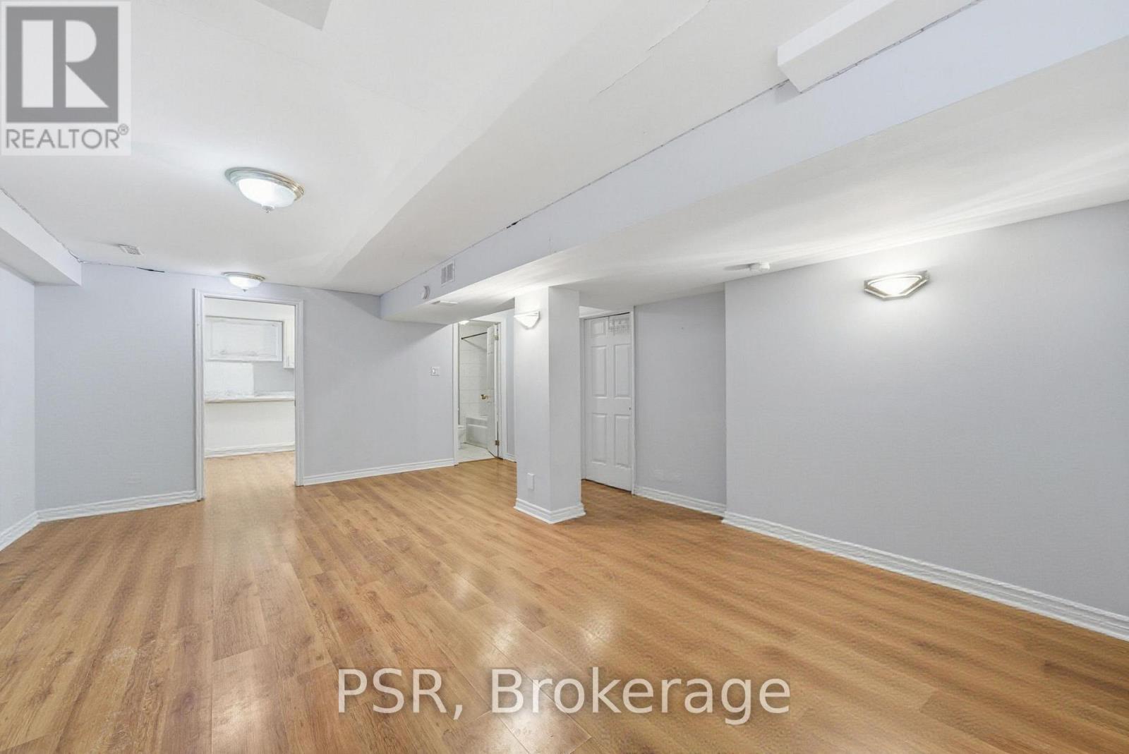 A spacious room with wooden flooring and white walls, labeled "PSR, Brokerage".