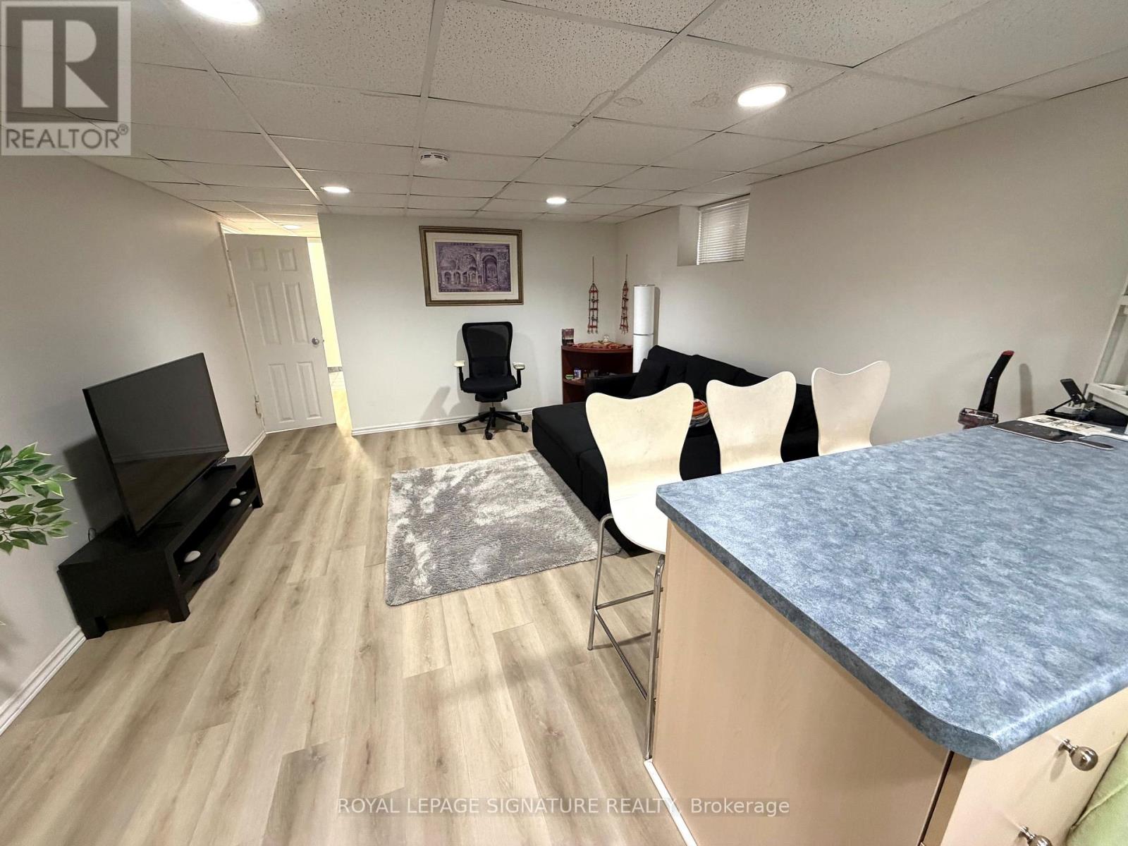 A realtor's office with a desk, chairs, and a television.