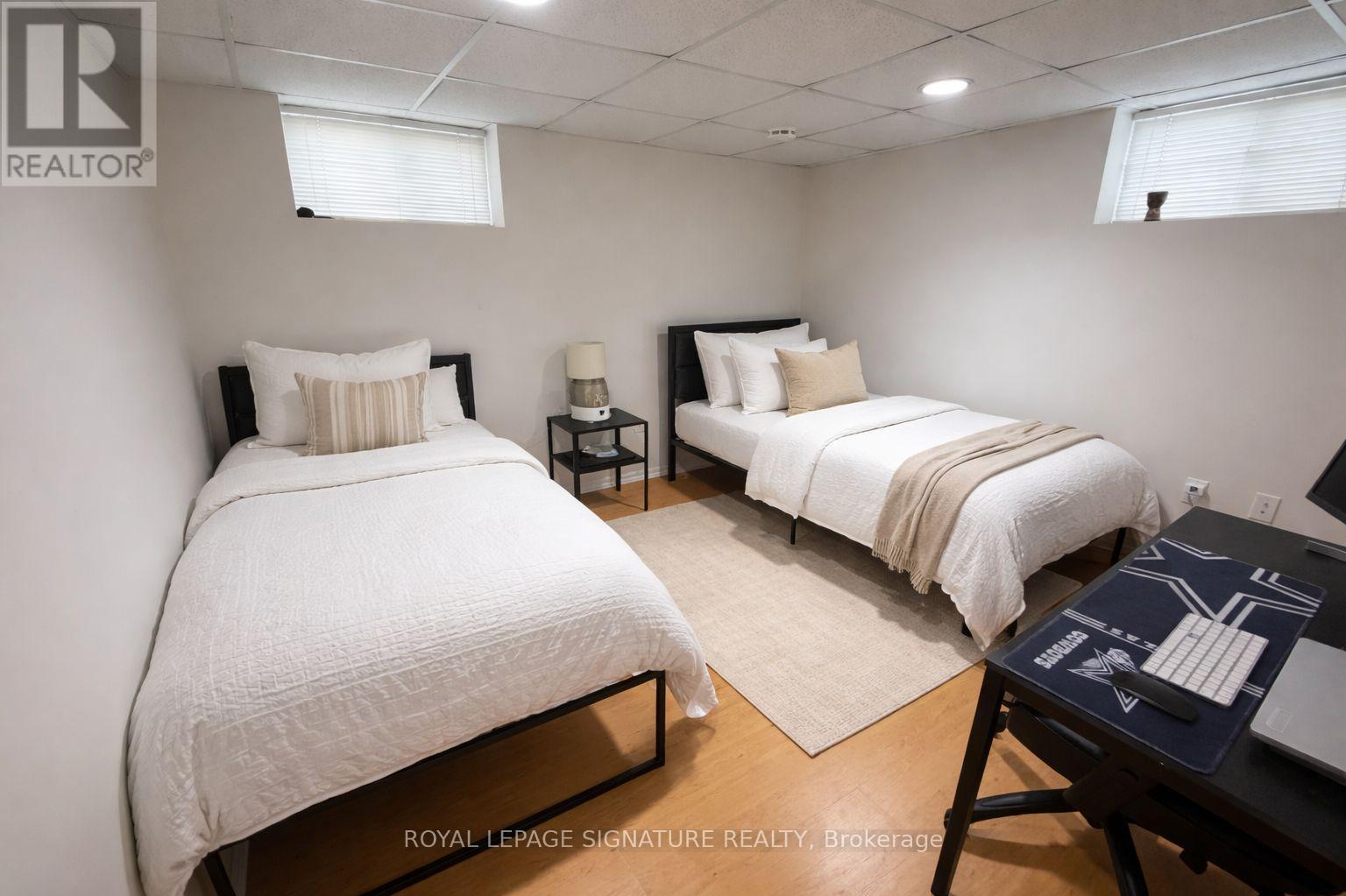 A bedroom with two beds and a desk.