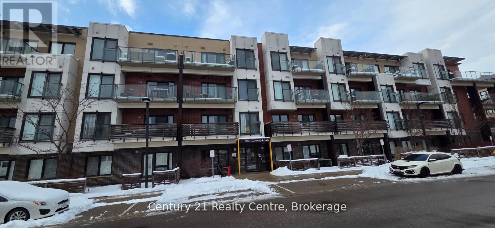 A white car is parked in front of a building with the sign Century 21 Realty Centre Brokerage.