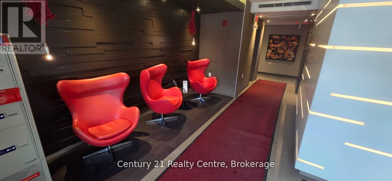A hallway with red chairs and a red carpet.