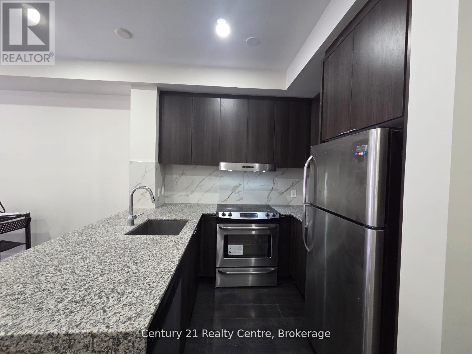A modern kitchen with a stainless steel refrigerator and a marble countertop.