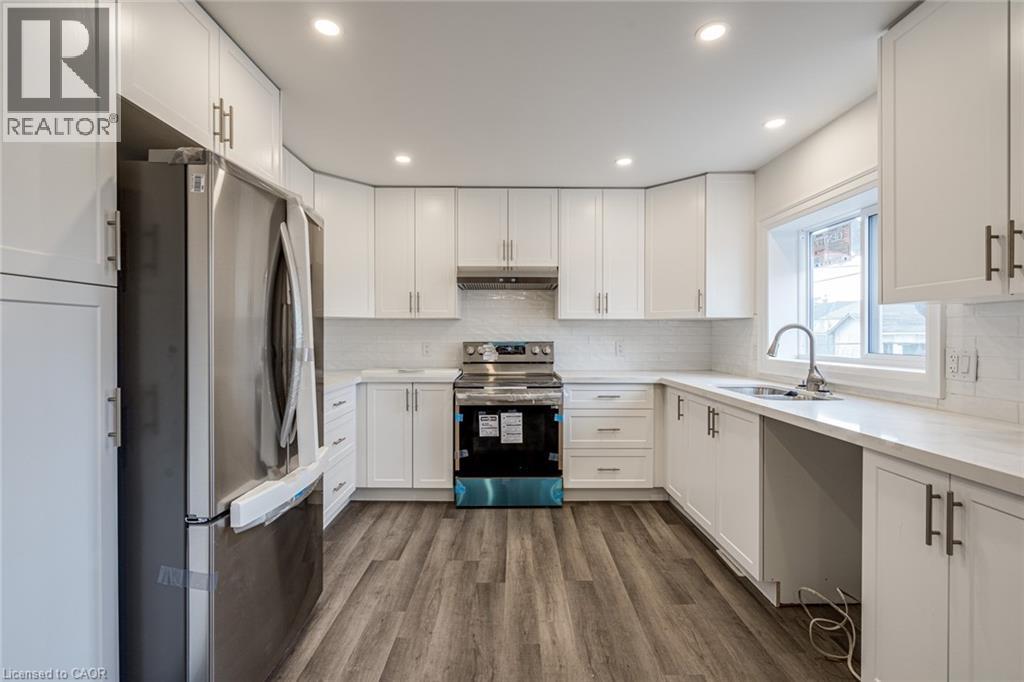 A modern kitchen with white cabinets and a wooden floor.
