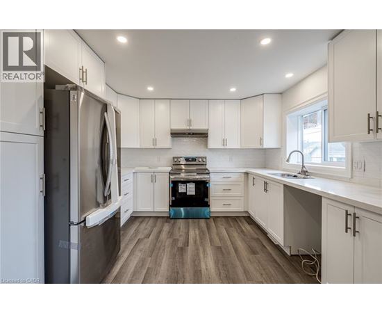 A modern kitchen with white cabinets and a wooden floor.