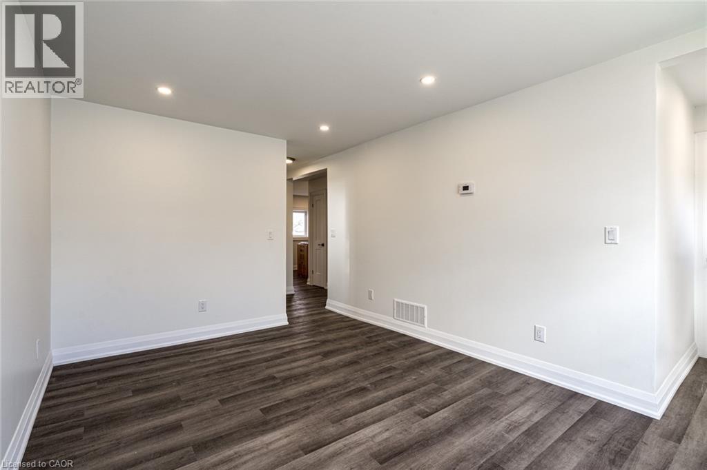 A spacious room with wooden flooring and white walls.