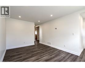 A spacious room with wooden flooring and white walls.