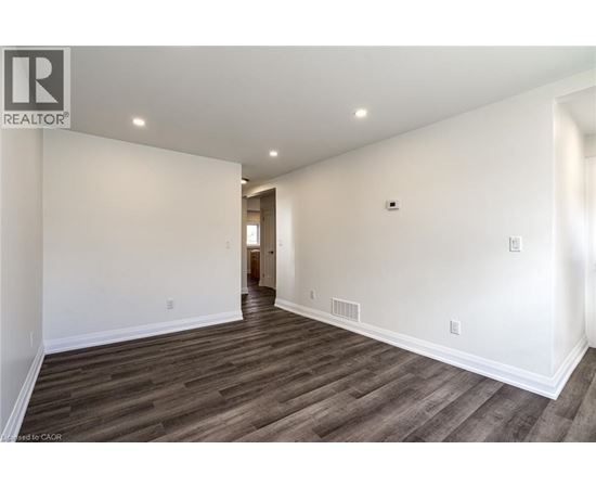 A spacious room with wooden flooring and white walls.