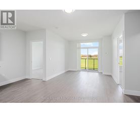 A spacious room with white walls and a large window overlooking a green fence.