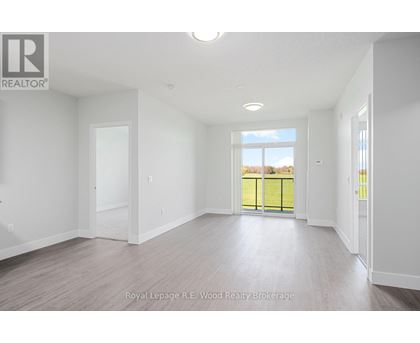 A spacious room with white walls and a large window overlooking a green fence.