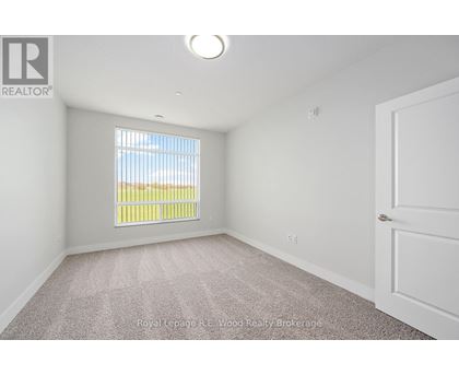 A white bedroom with a window and carpeted floor.