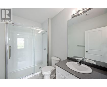 A white toilet sits in a bathroom next to a sink and a walk-in shower.