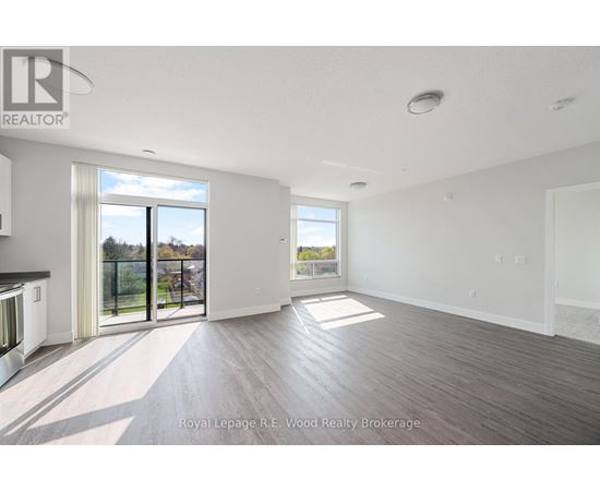A spacious room with wooden flooring and a large window overlooking a balcony.
