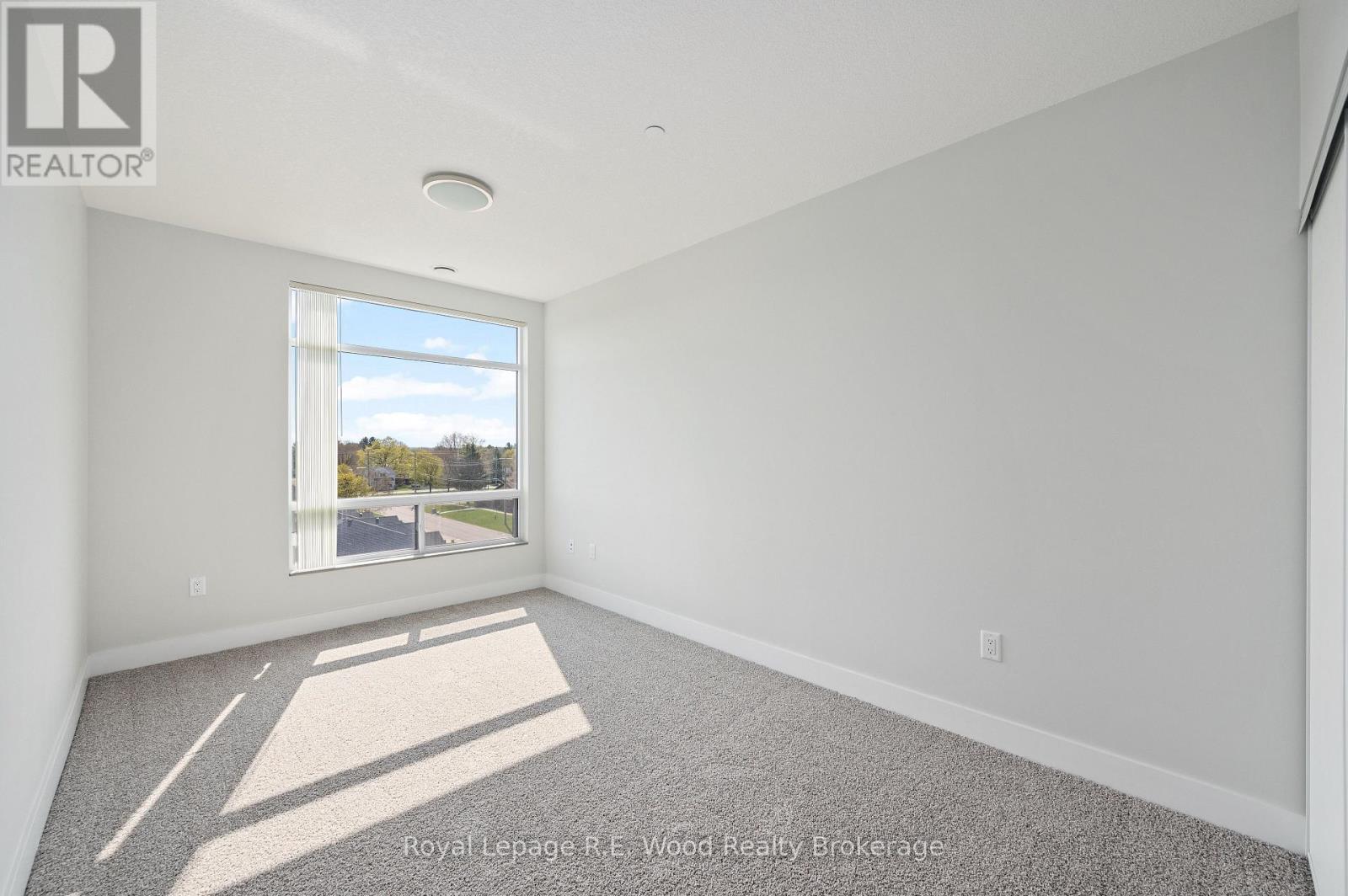 A well lit empty room with a window and carpet on the floor.