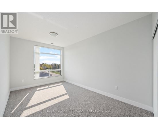 A well lit empty room with a window and carpet on the floor.