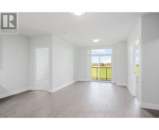 A spacious room with white walls and a large window overlooking a green fence.