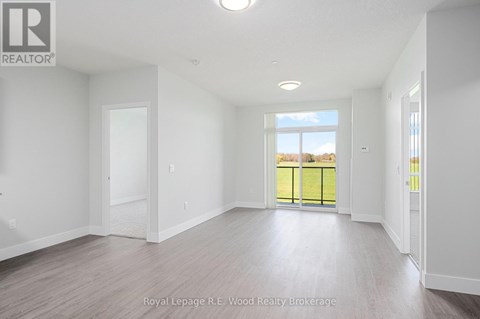 A spacious room with white walls and a large window overlooking a green fence.