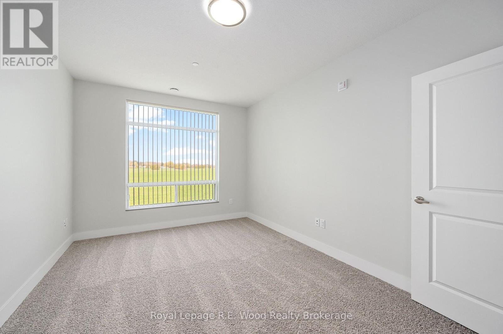 A white bedroom with a window and carpeted floor.