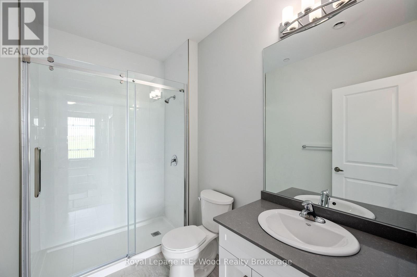 A white toilet sits in a bathroom next to a sink and a walk-in shower.
