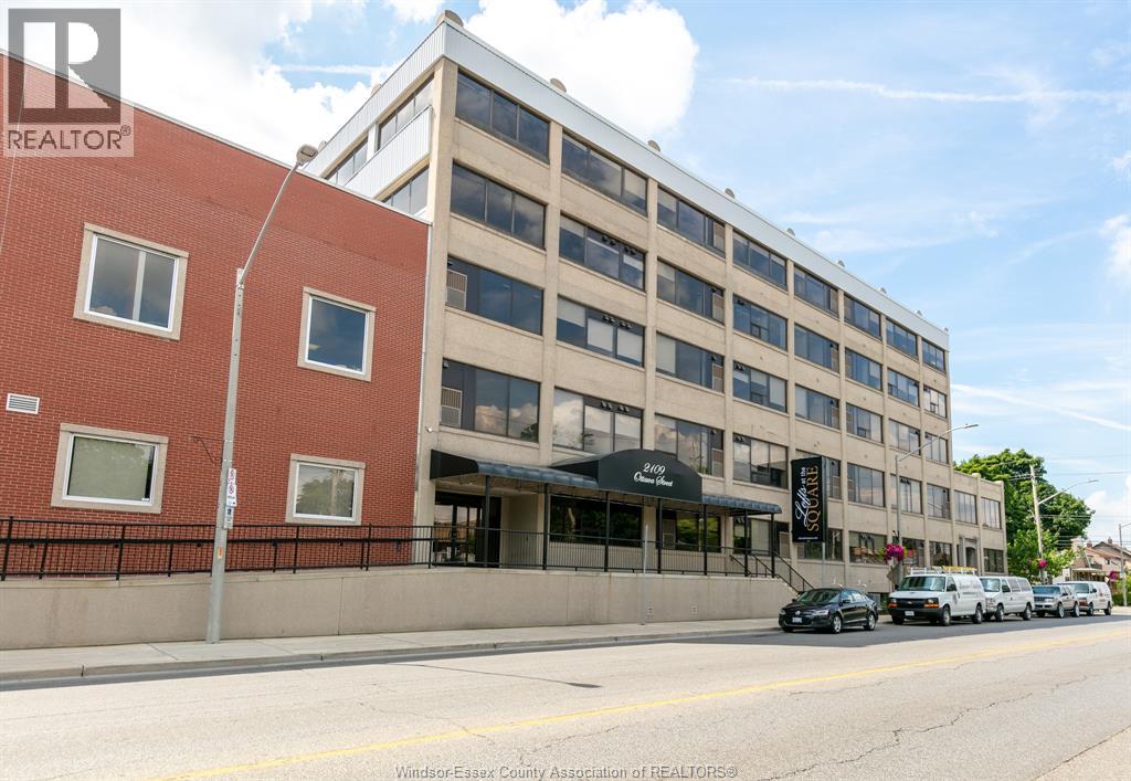 A building with a black awning and a sign that says "REALTOR" is on the corner of a street.