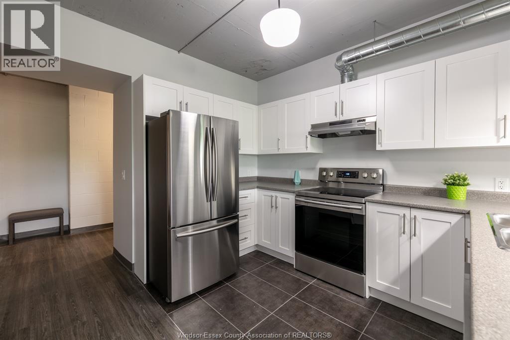 A modern kitchen with a stainless steel refrigerator and white cabinets.