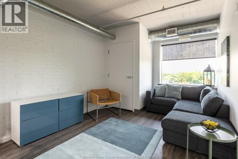 A living room with a blue rug and a grey couch.