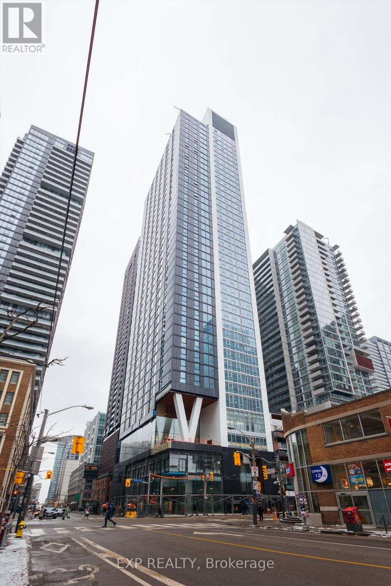 A tall building with a blue glass facade stands in the middle of a city street.