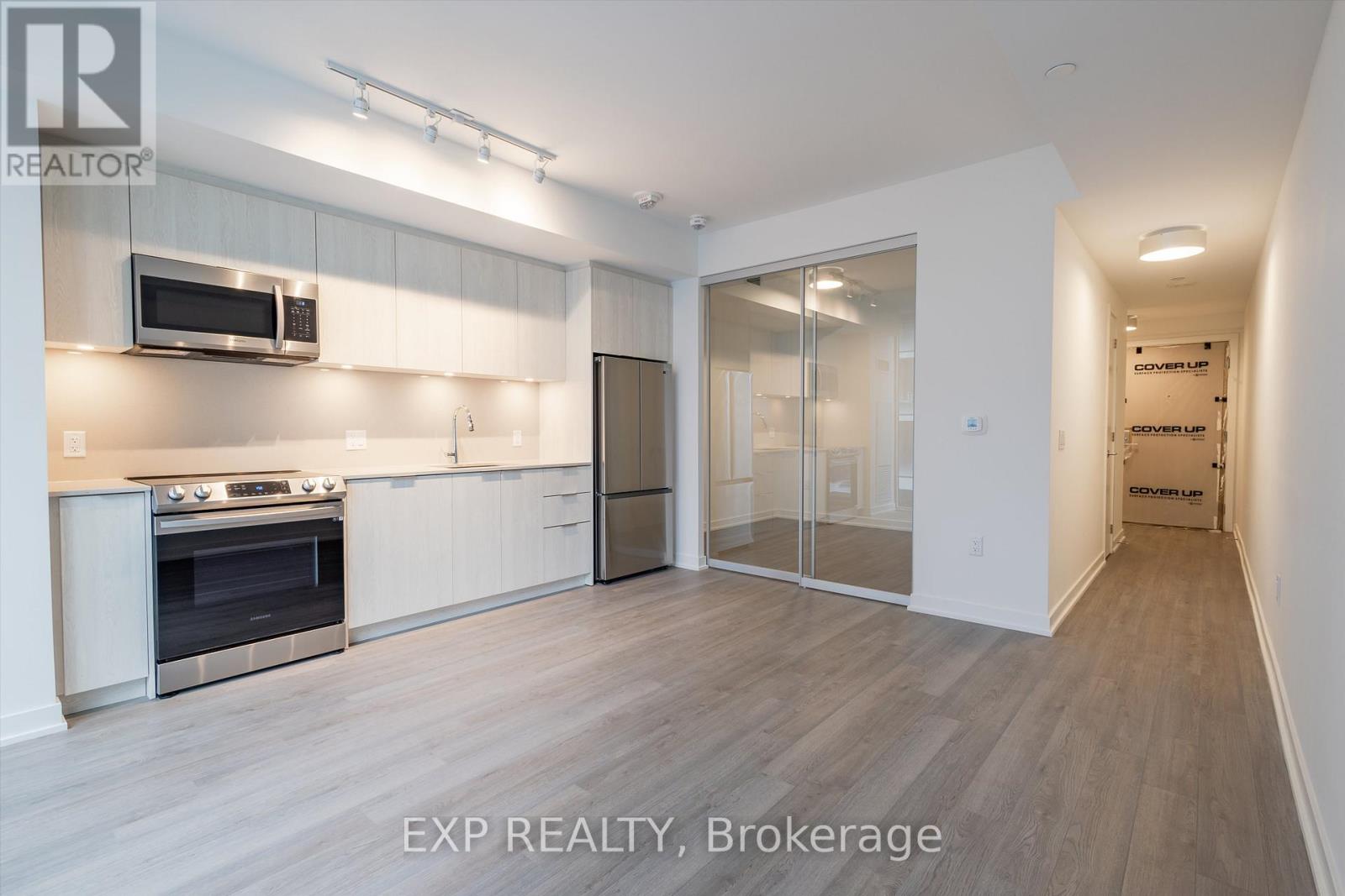 A kitchen with white cabinets and a stainless steel refrigerator.