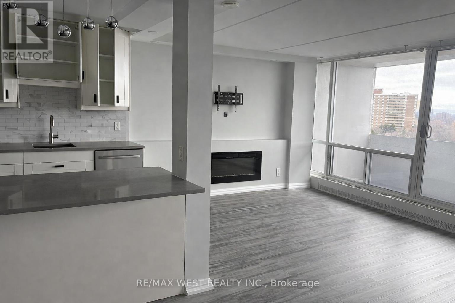 A modern kitchen with a large island and a flat screen TV mounted on the wall.