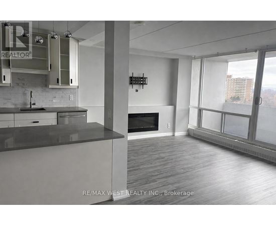 A modern kitchen with a large island and a flat screen TV mounted on the wall.