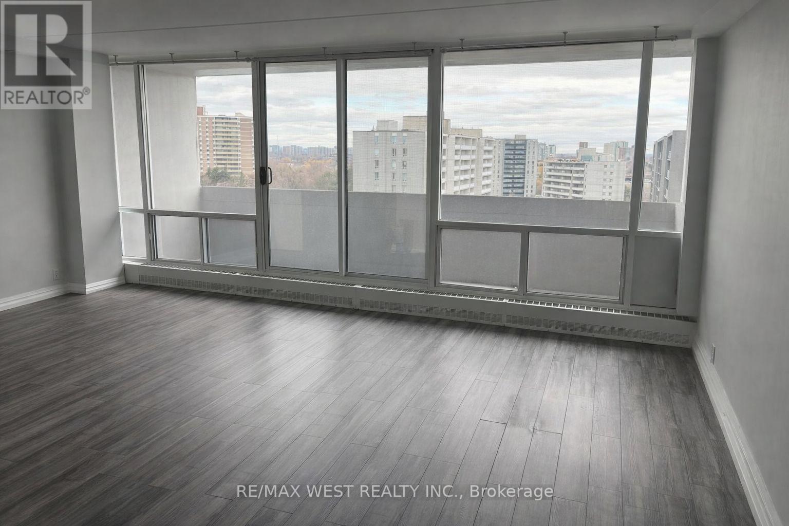 A room with a large window and wooden flooring.