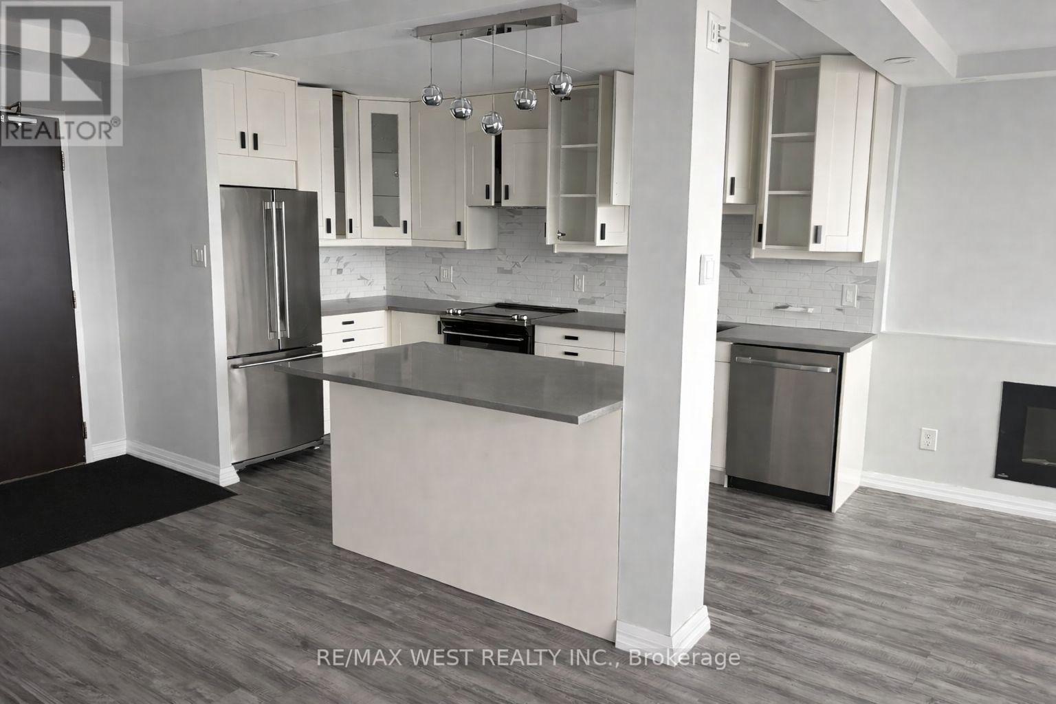 A kitchen with a refrigerator, oven, and cabinets.