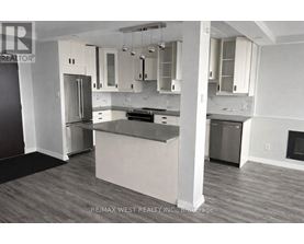 A kitchen with a refrigerator, oven, and cabinets.