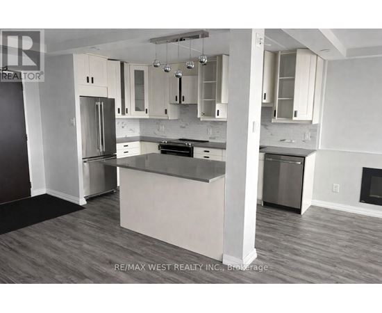 A kitchen with a refrigerator, oven, and cabinets.