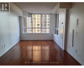 A room with wooden floors and a large window overlooking a building.