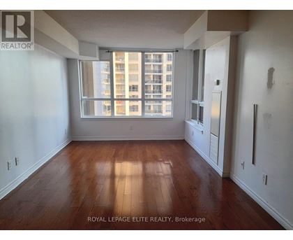 A room with wooden floors and a large window overlooking a building.