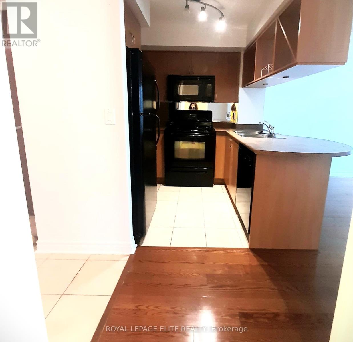A kitchen with a black refrigerator and wooden floors.