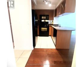 A kitchen with a black refrigerator and wooden floors.