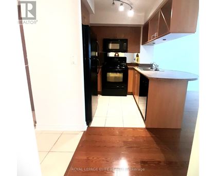 A kitchen with a black refrigerator and wooden floors.