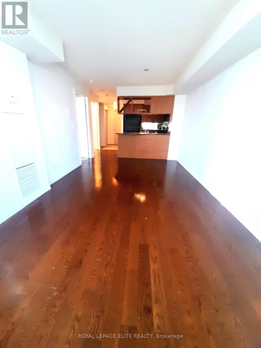 A long hallway with wood floors and white walls.