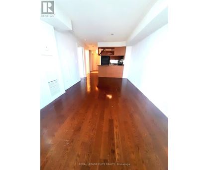 A long hallway with wood floors and white walls.