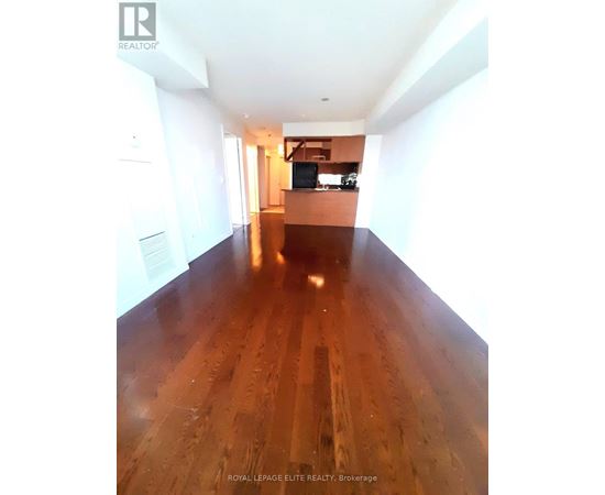 A long hallway with wood floors and white walls.