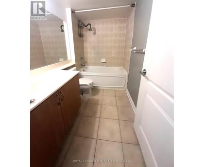 A white bathtub is in a bathroom with white walls and a white toilet.